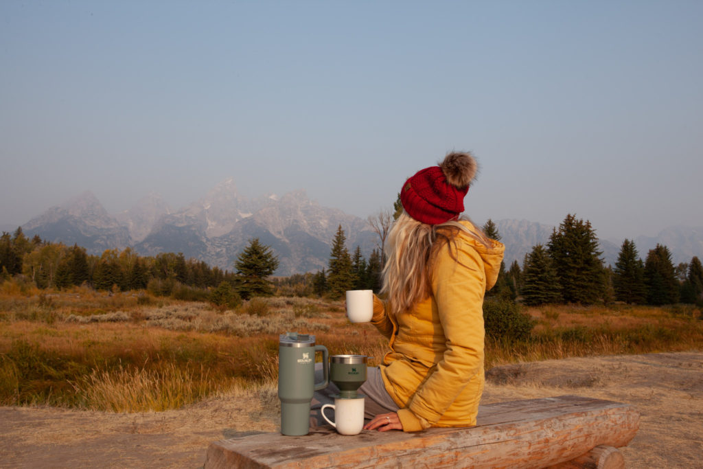 Chelsey in front of the Grand Tetons with her Stanley pour over coffee maker