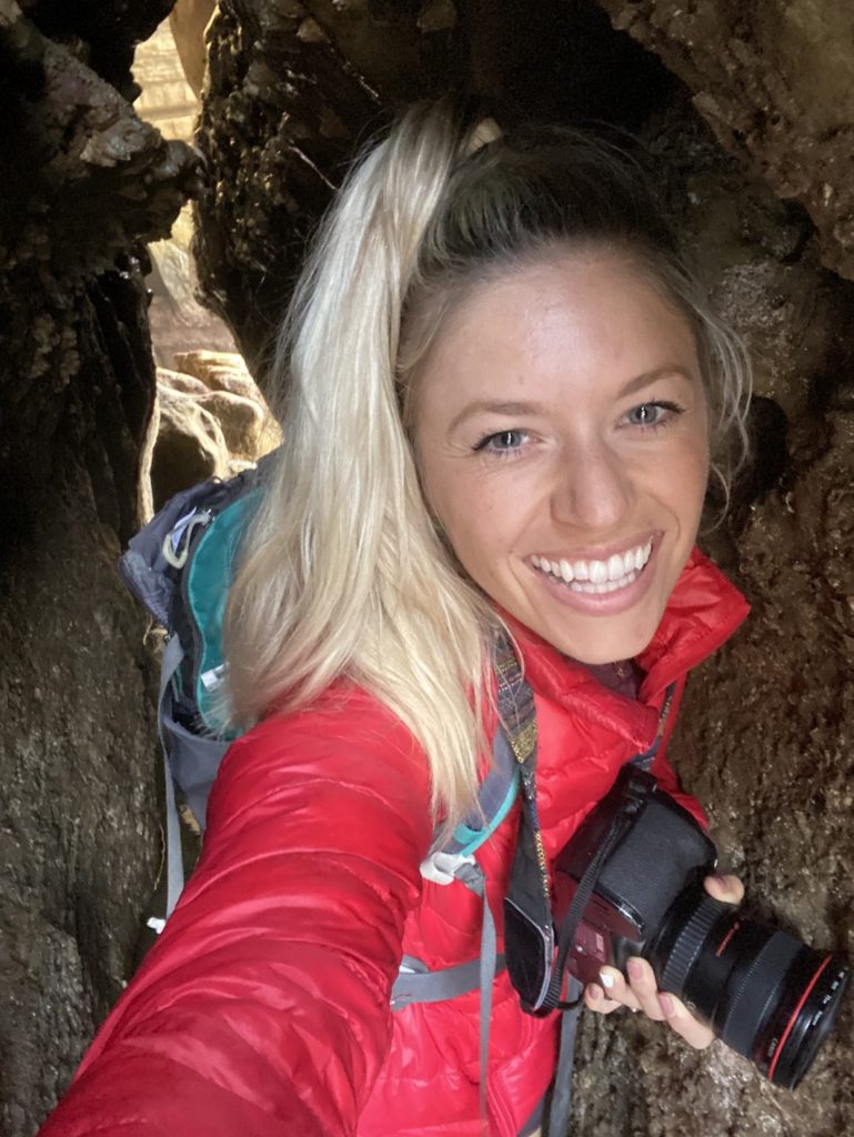 Girl crawling through sunset cliffs cave