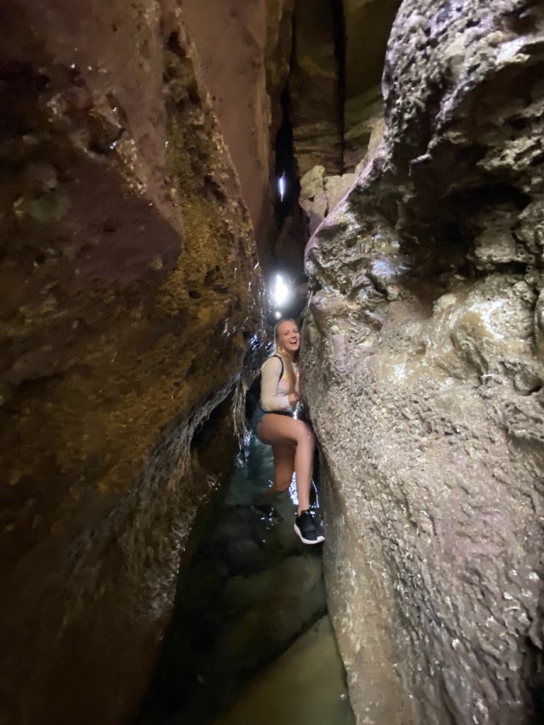 Girl crawling through sunset cliffs cave