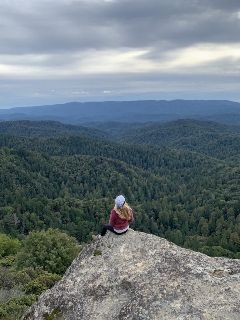 Chelsey sitting on a rock overlooking the trees in Castle Rock Park