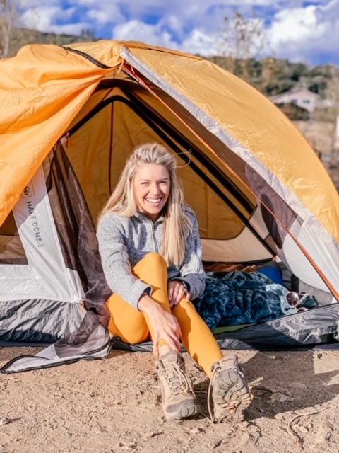 Girl sitting in front of tent that she got from a discounted outdoor gear website