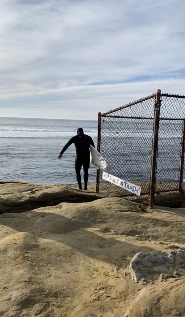 Surfer walking down on Sunset Cliffs