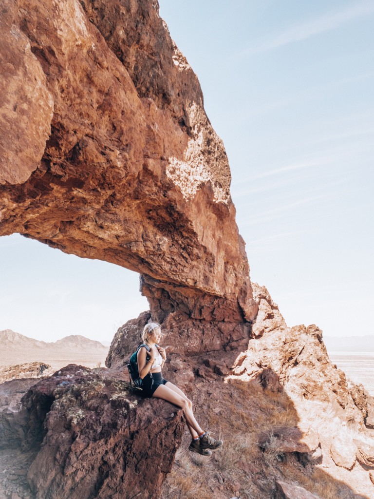 Girl sitting on a rock with a sand rock arch over her