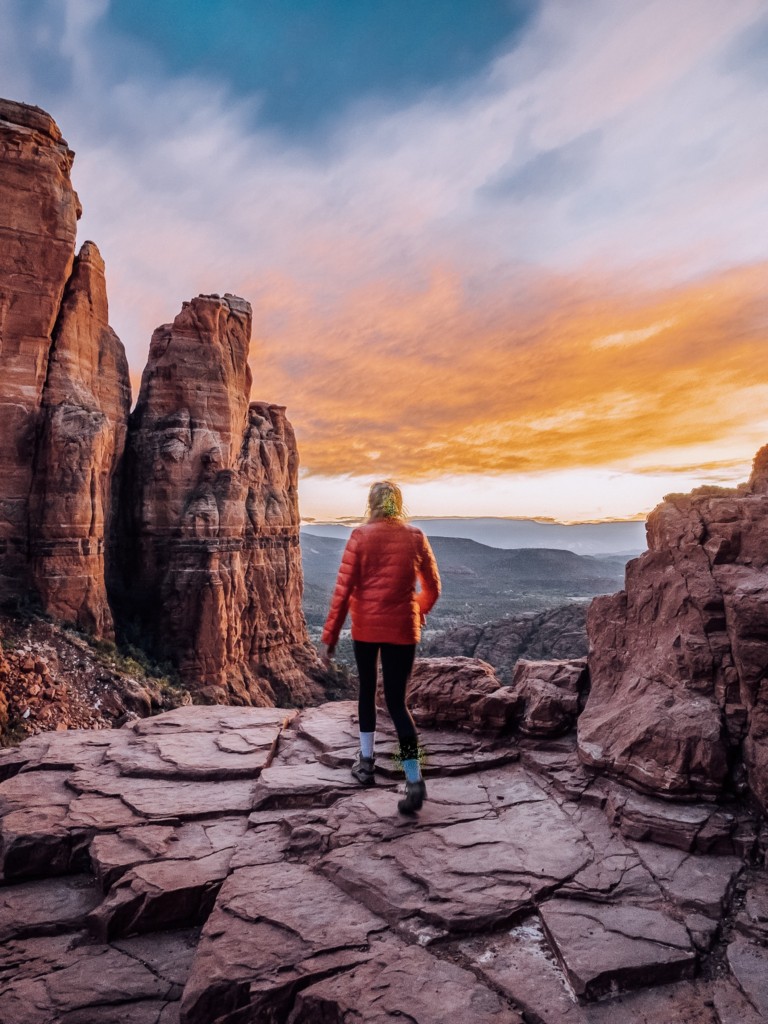 Girl at the top of Cathedral Rock hike in Sedona with a sunset in the background