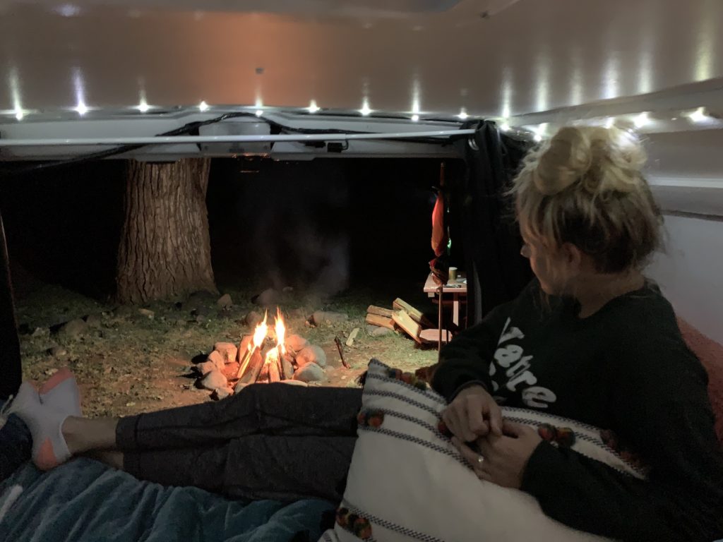 Girl sitting in campervan looking at bonfire