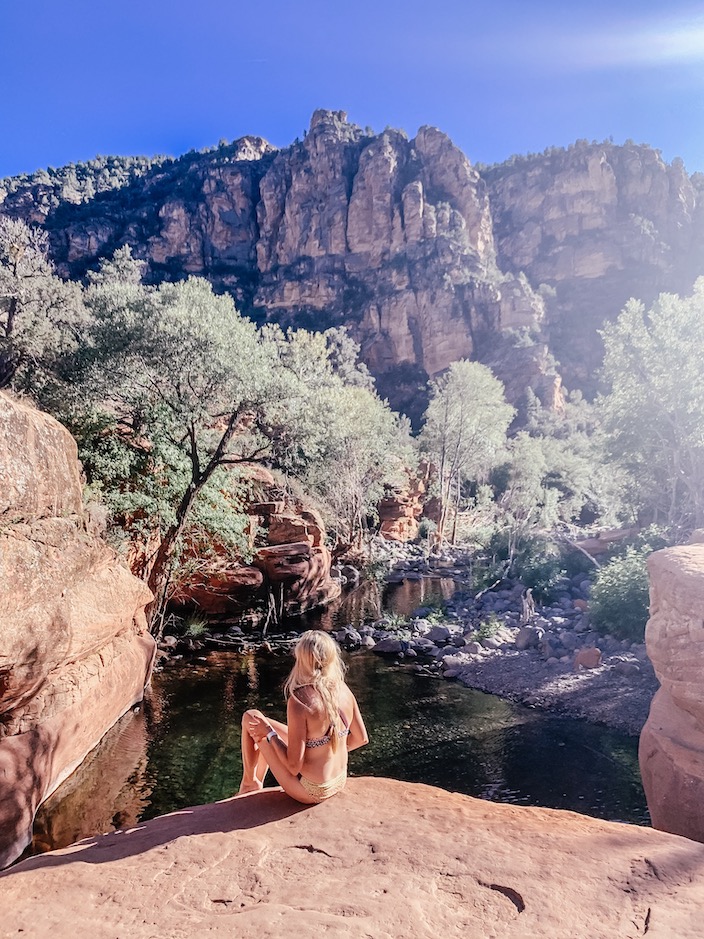 Girl sitting on rock at wet beaver creak in Sedona as part of her Sedona travel trip