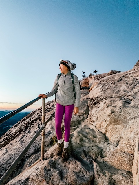 Girl hiking with a headlamp on her head as a headlamp is an essential camping gear item