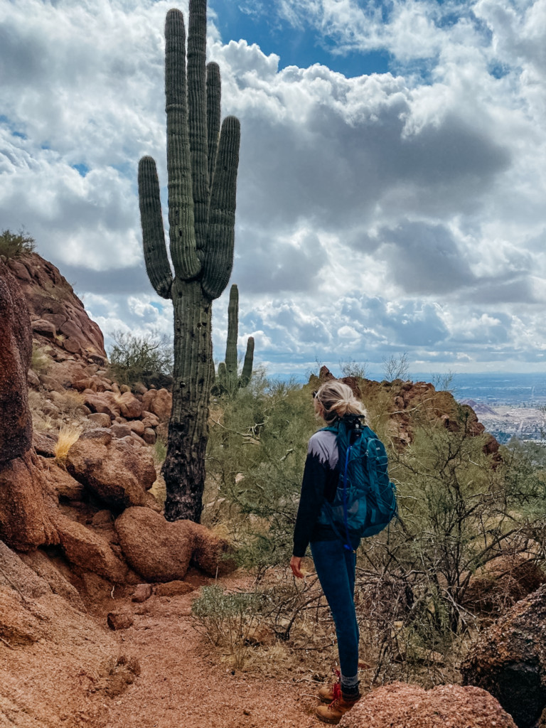 Girl standing in front of a cactus on her hike up Camelback mountain in Phoenix