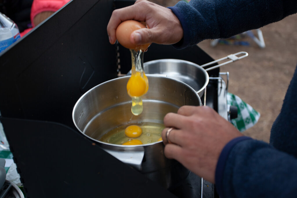 Cracking an egg into the cookware when cammping. 