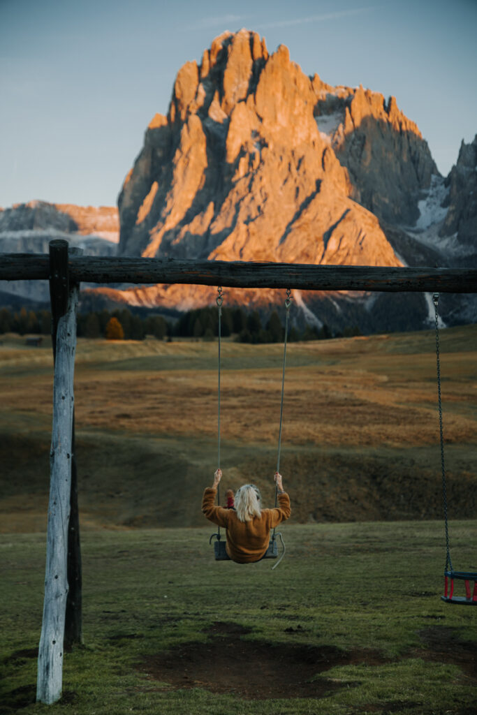Chelsey Explores swinging on a playground at Malga Sanon in the Dolomites