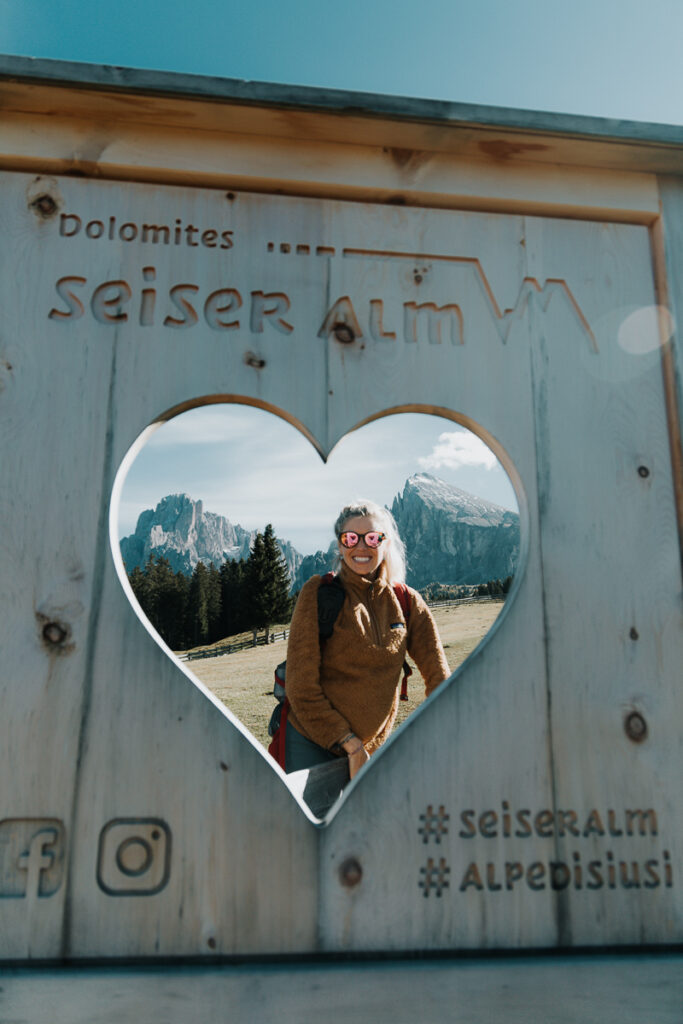 Chelsey Explores sitting in a heart shaped cutout at Seiser Alm in the Dolomites