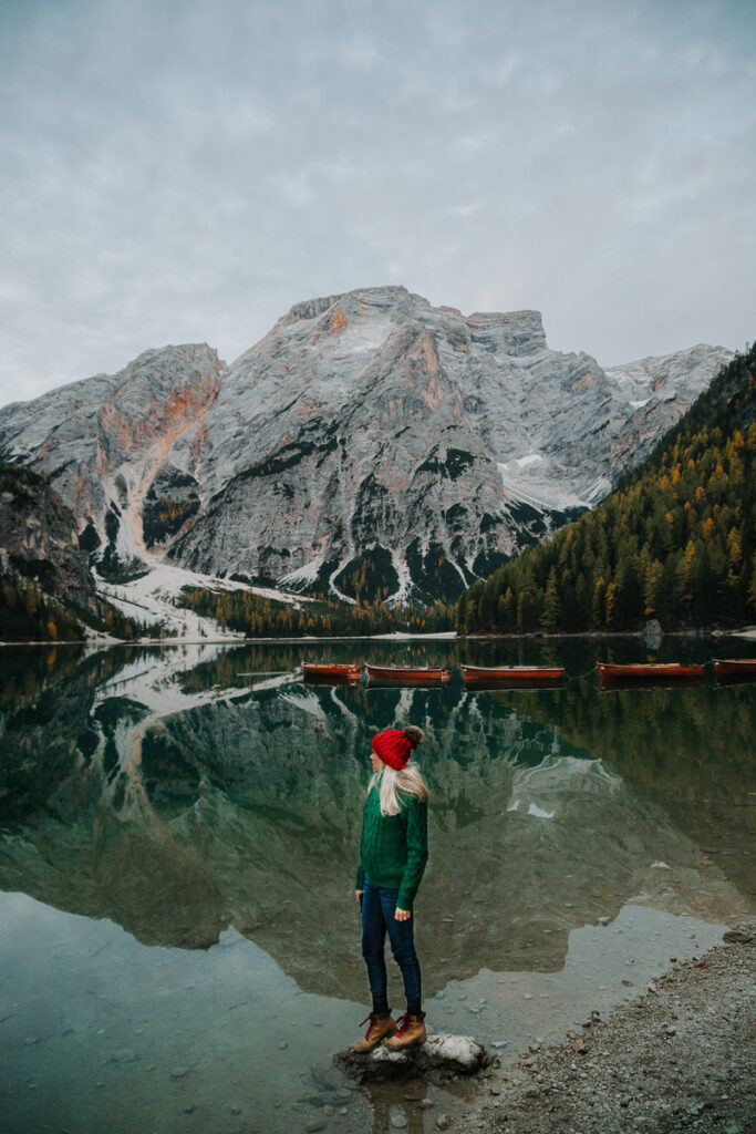 Chelsey Explores standing on a rock looking out at the lake Lago di Braies at sunrise