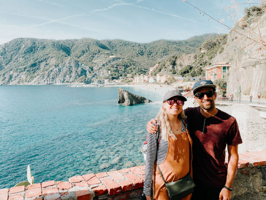 Couple standing with a view of Monterosso beach in the background