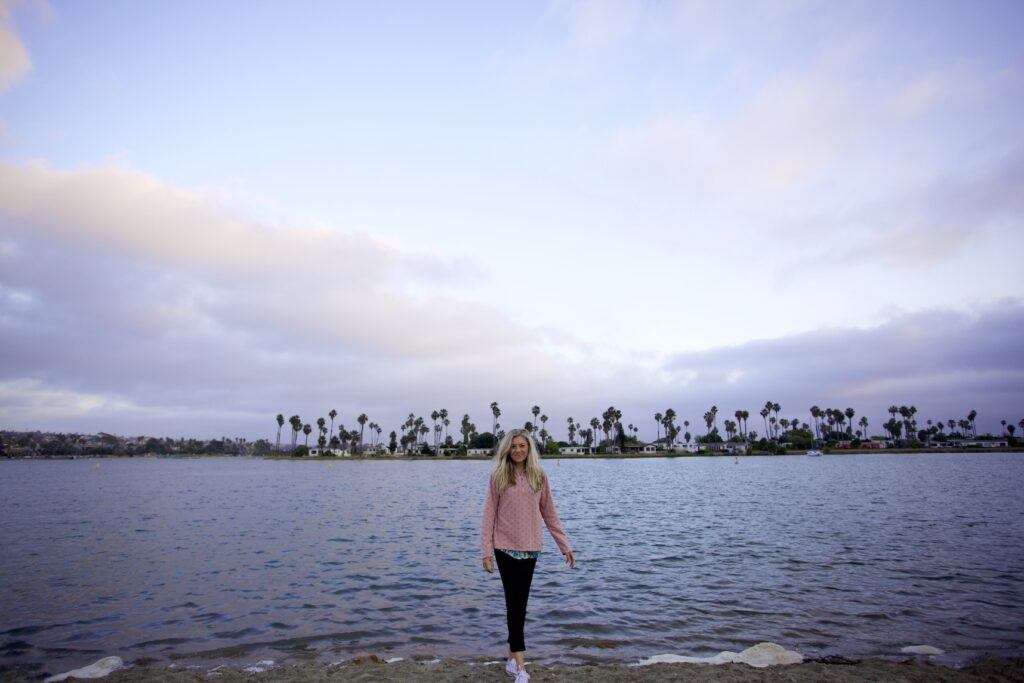 Girl standing on Mission Bay beach at sunset time