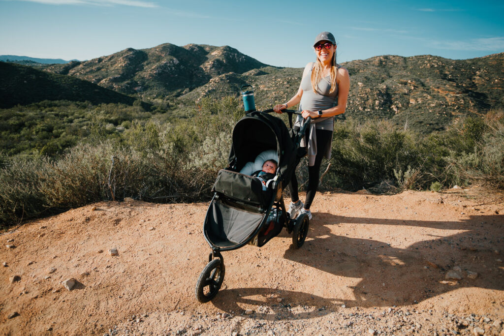 Girl walking her baby along the stroller friendly Lake Poway trail in San Diego