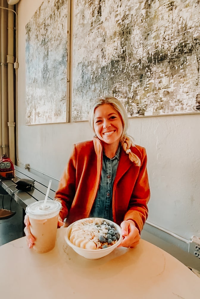 Girl eating an acai bowl and drinking coffee at Holsem Coffee