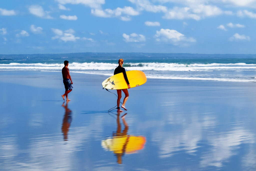 girl walking into the ocean to go surfing