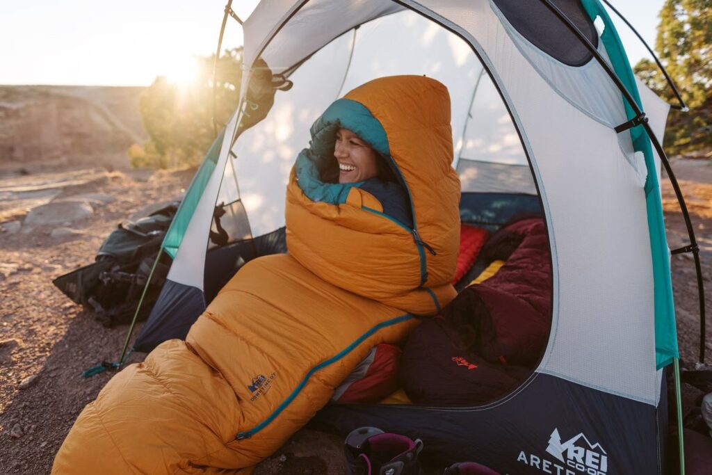 female in tent wrapped up in a sleeping bag