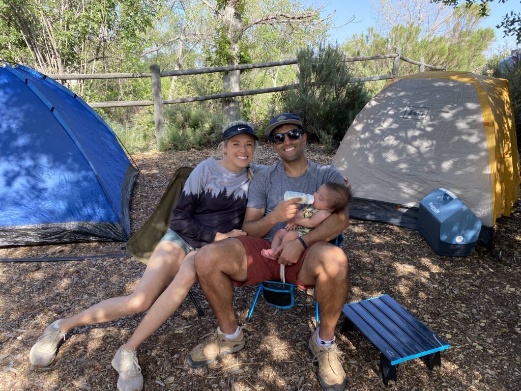 family sitting in camping chairs together with baby on lap