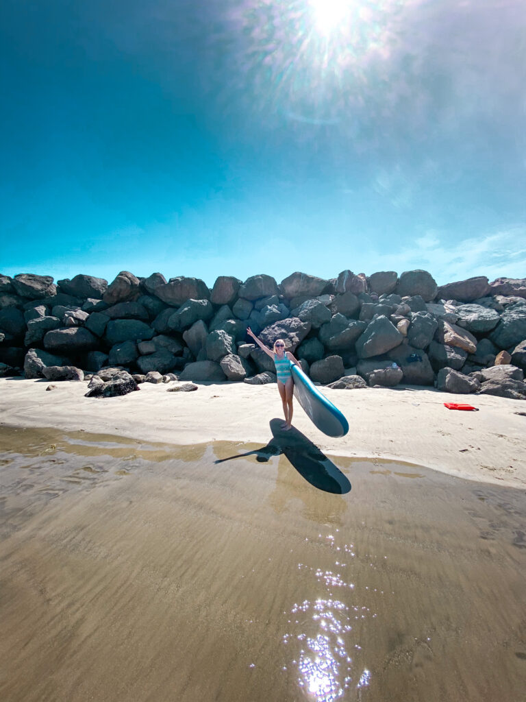 girl with a surfboard on the beach at oceanside