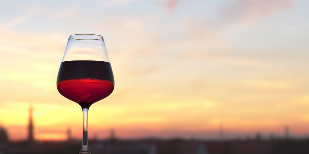 glass of red wine with the sunset in the background